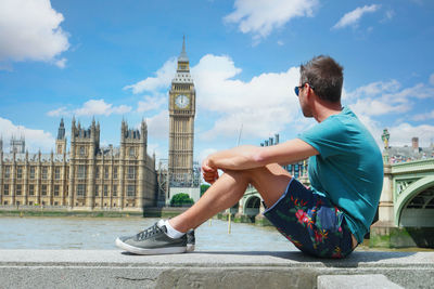 Side view of young man standing against built structures