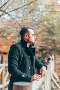 Man looking away while standing by railing