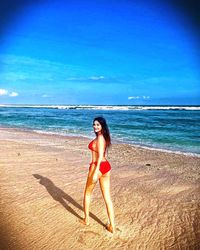 Full length of woman at beach against blue sky