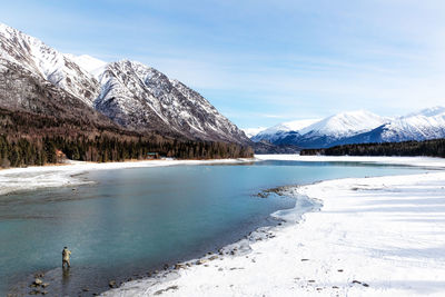 Scenic view of frozen lake by snowcapped mountains against sky