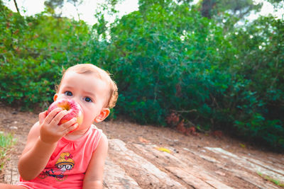 Portrait of cute baby girl eating apple