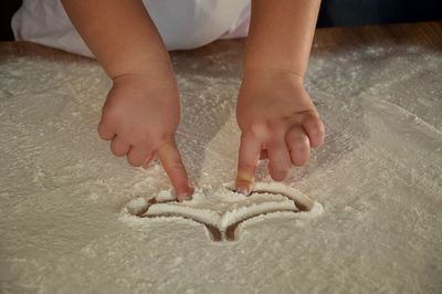 Cropped hands of girl playing with flour on table