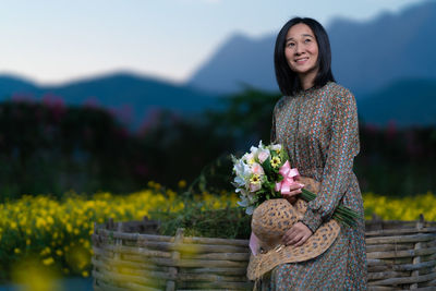 Young woman standing by flowering plants