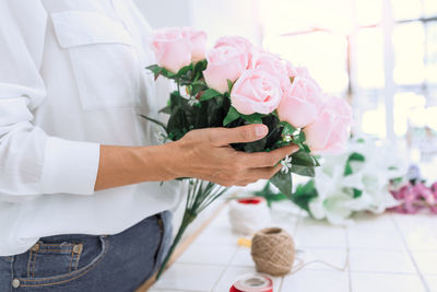 Midsection of florist making rose bouquet