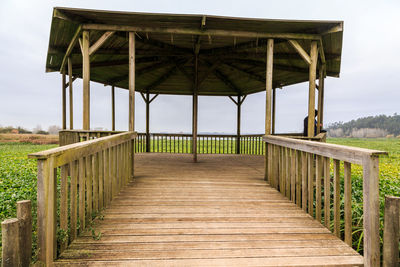 Wooden footbridge on pier against sky