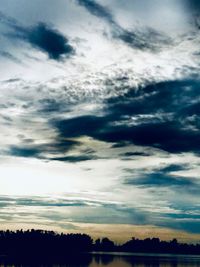Low angle view of silhouette trees against dramatic sky