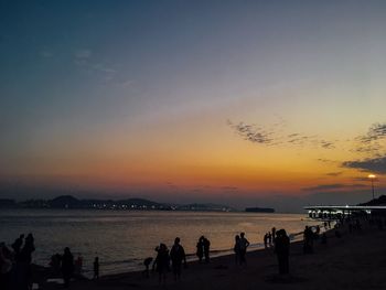 Silhouette people on beach against sky during sunset