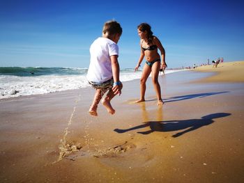 Full length of girl with brother at beach