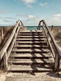 Staircase leading towards sea against sky