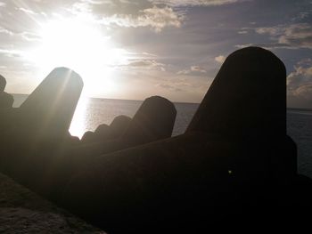 Close-up of silhouette rocks by sea against sky during sunset