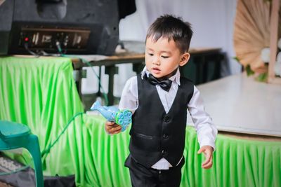 Cute boy holding toy standing at home