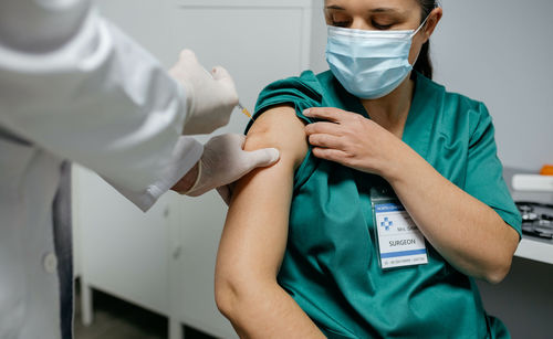 Midsection of doctor vaccinating patient in clinic