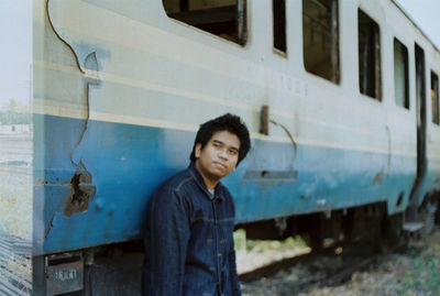 Young man standing by abandoned train