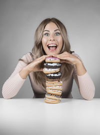 Portrait of young woman sitting against gray background