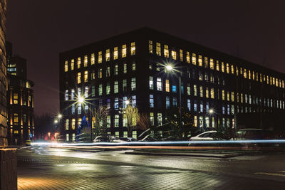 Illuminated street amidst buildings in city at night