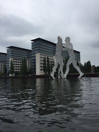 Statue by buildings against sky in city