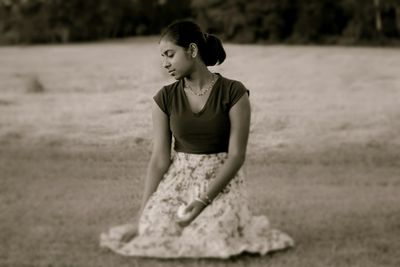 Sad young woman sitting at lakeshore