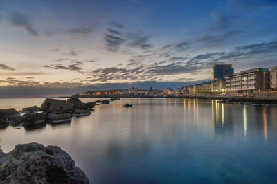 Scenic view of sea and buildings against sky at sunset