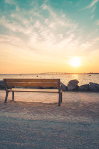 Isolated public bench at sunrise. re island bridge in the background