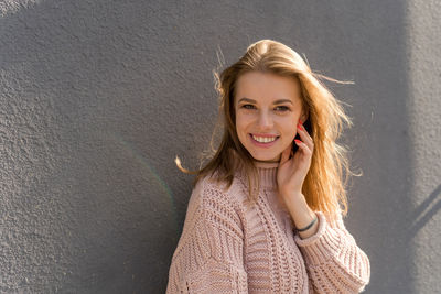 Portrait of young woman standing against wall