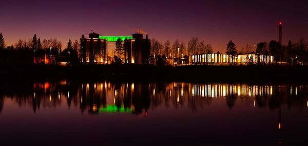 Scenic view of lake by buildings against sky at night