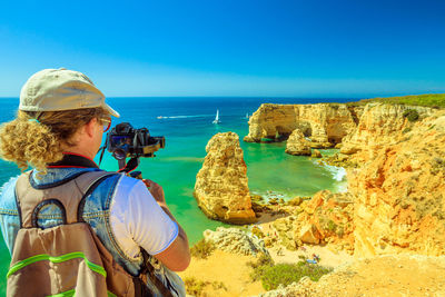 Woman photographing sea against sky