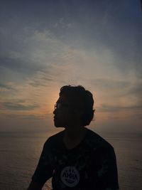 Man standing on beach against sky during sunset