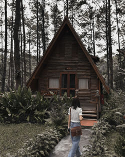 Rear view of woman standing by plants in forest