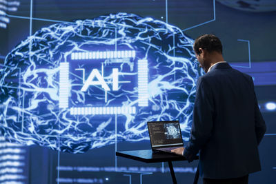 Digital composite image of businessman using laptop