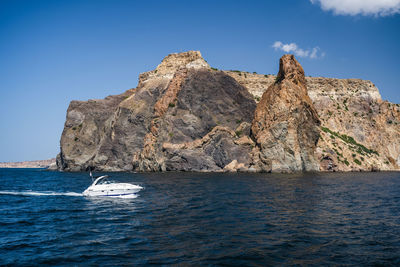 Speed boat in black sea with volcanic rocks of cape fiolent in background, sevastopol crimea