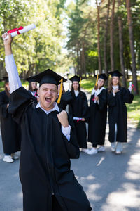 Happy young caucasian man celebrating graduation. crowd of students graduates outdoors