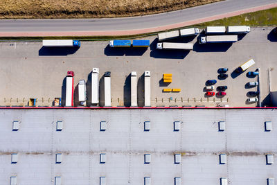 Aerial shot of truck with attached semi trailer leaving industrial warehouse/ storage 