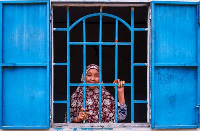 Portrait of woman holding blue window