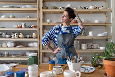 Pensive thoughtful italian woman pottery artist wearing apron thinking about something in studio