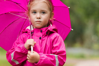 Portrait of cute girl holding umbrella standing outdoors