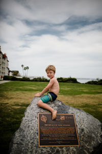 Full length of boy sitting on land against sky