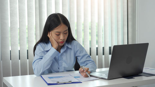 Young woman using mobile phone while sitting on table