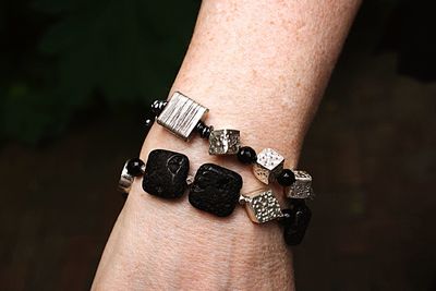 Cropped hand wearing bracelet against black background