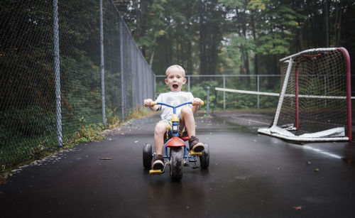 Portrait of playful boy riding tricycle at playground