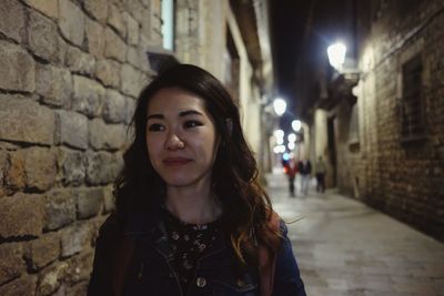 Portrait of young woman standing against brick wall