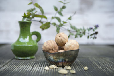 Close-up of dried lemons in bowl with vase on table