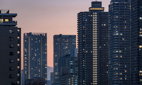 Modern buildings in city against sky at dusk