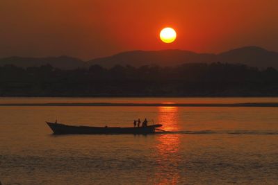 Silhouette boat in sea against sky during sunset