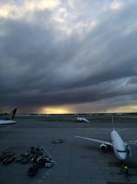 Airplane on airport runway against sky during sunset