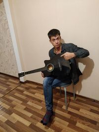 Portrait of man playing guitar at home