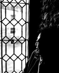 Close-up portrait of a boy looking through window at home
