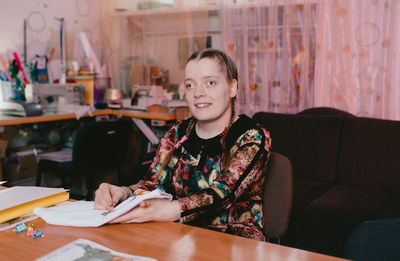 Portrait of smiling young woman sitting on table