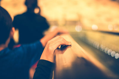 Cropped hand by boy touching railing