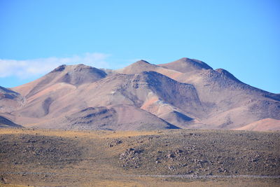 Scenic view of volcanic mountain against blue sky