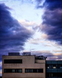 Low angle view of buildings against cloudy sky